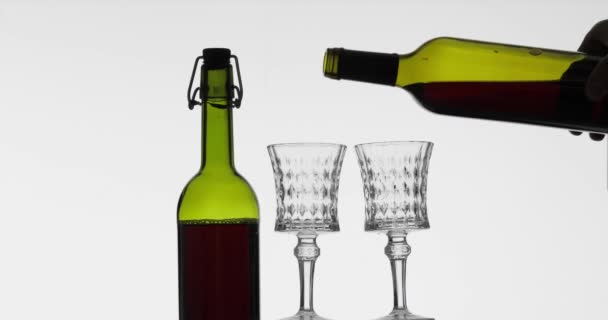 Rose wine. Red wine pour in two wine glasses over white background — Stock Video