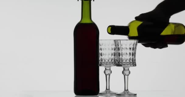 Rose wine. Red wine pour in two wine glasses over white background — Stock Video