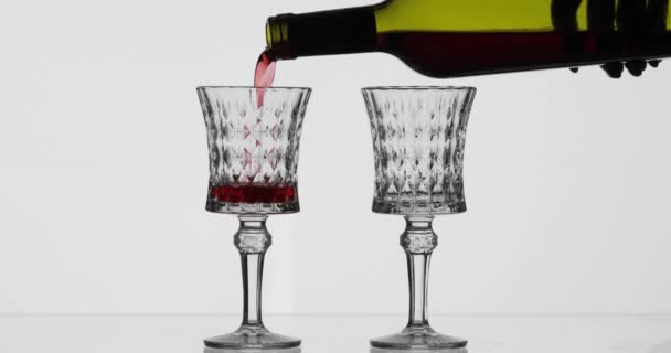 Рожеве вино. Червоне вино наливають у два келихи для вина на білому тлі — стокове відео