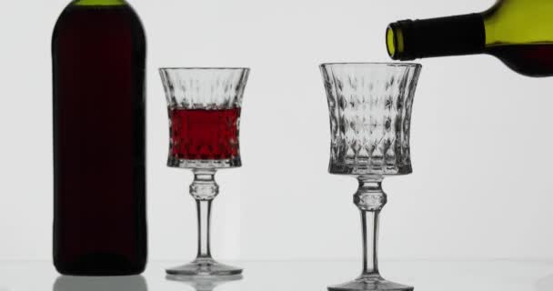 Рожеве вино. Червоне вино вливають у келих для вина на білому тлі — стокове відео
