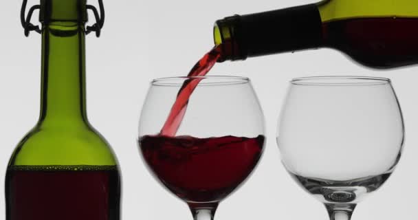 Rosenwein. Rotwein in zwei Weingläser auf weißem Hintergrund gießen — Stockvideo