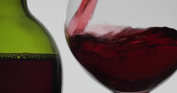 Рожеве вино. Червоне вино вливають у келих для вина на білому тлі — стокове відео