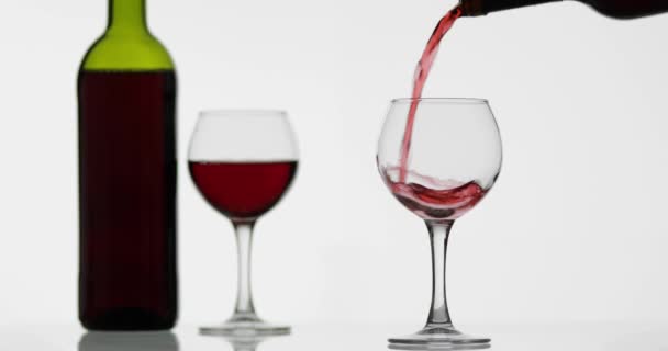 Розовое вино. Красное вино наливают в бокал вина на белом фоне — стоковое видео