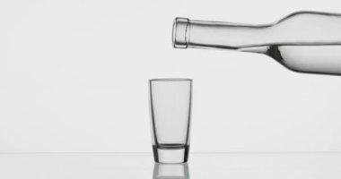 Şişeden bardağa bir bardak votka döküyorum. Beyaz arka plan