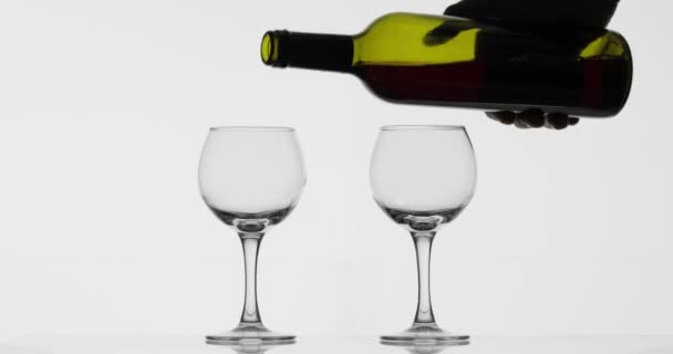 Розовое вино. Красное вино наливают в два бокала вина на белом фоне — стоковое видео