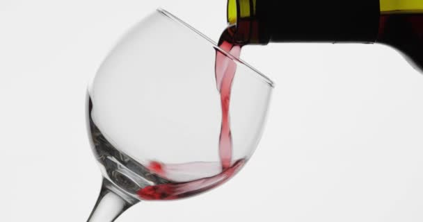 Vino rosa. Vino tinto verter en copa de vino sobre fondo blanco — Vídeo de stock