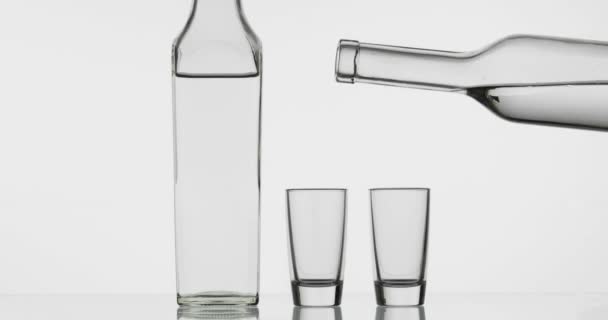 Felöntése két lövés a vodka egy üveg pohárba. Fehér háttér — Stock videók