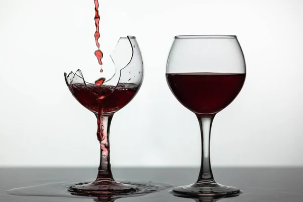 Törött borospohárba ömlött vörösbor nedves felületen. Rózsa-bor pour — Stock Fotó