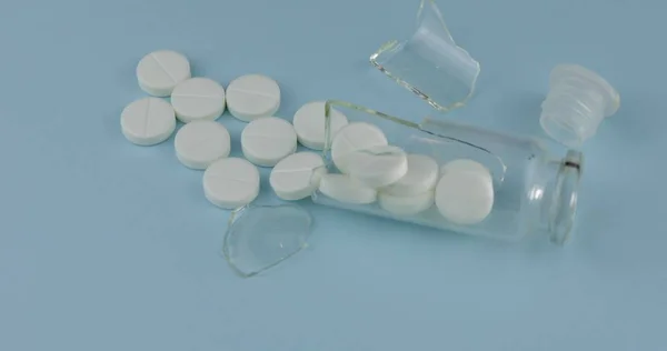 Vaso di vetro rotto con molte pillole e farmaci su sfondo blu — Foto Stock