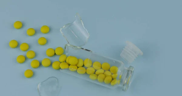 Σπασμένο γυάλινο βάζο με πολλά χάπια και φάρμακα σε μπλε φόντο — Φωτογραφία Αρχείου