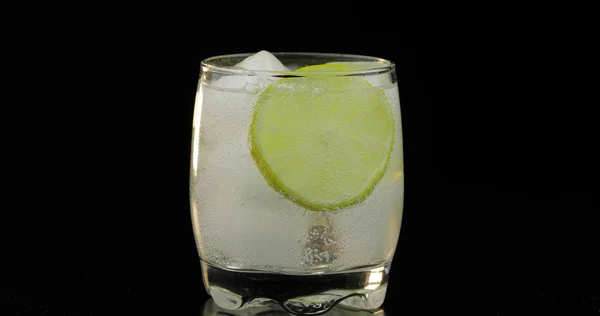 Una bebida refrescante en un vaso con hielo y lima. Agua gaseosa tónica con gas —  Fotos de Stock