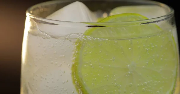 Una bebida refrescante en un vaso con hielo y lima. Agua gaseosa tónica con gas —  Fotos de Stock