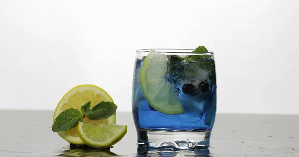 Vidrio con bebida azul fría con hojas de menta, lima, limón, grosellas negras —  Fotos de Stock