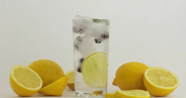 Vaso con bebida fría. Limón, cubitos de hielo y grosella negra en un vaso de agua —  Fotos de Stock