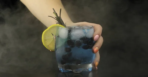Woman hand takes refreshing soda lemonade blue cocktail