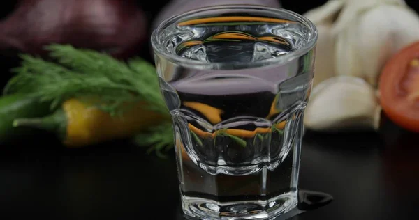 Bebida alcohólica vodka en vaso de chupito. Fondo con verduras —  Fotos de Stock