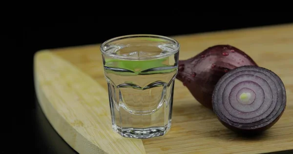 Bebida alcohólica vodka en vaso de chupito en tabla de cortar con cebolla —  Fotos de Stock