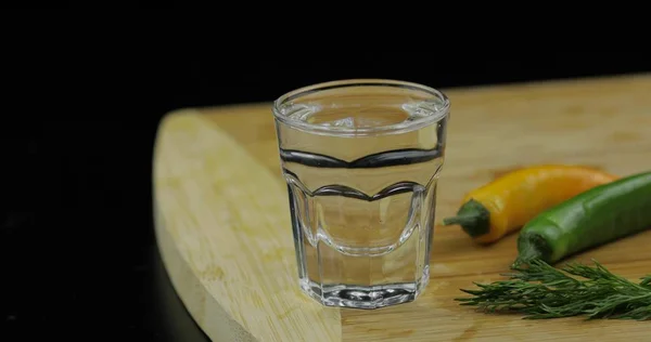 Vodka con alcohol en vaso de chupito sobre tabla de cortar con pimiento picante —  Fotos de Stock