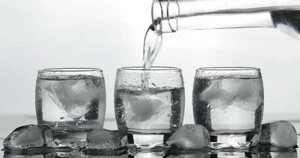 Derramando vodka em vidro com gelo. Fundo preto — Fotografia de Stock