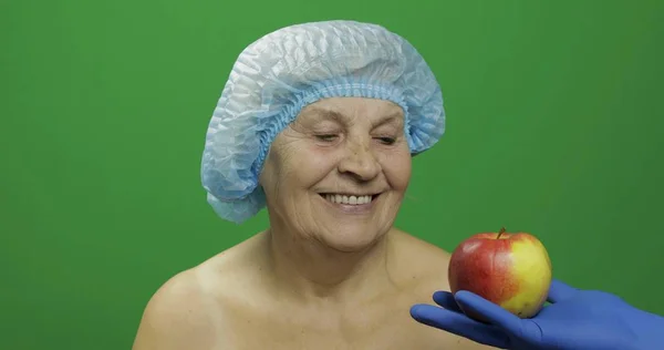 Äldre kvinnlig dam i skyddshatt. Läkare visar henne ett äpple — Stockfoto