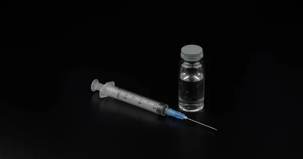 Jeringa, ampolla con vacunación sobre fondo negro — Foto de Stock