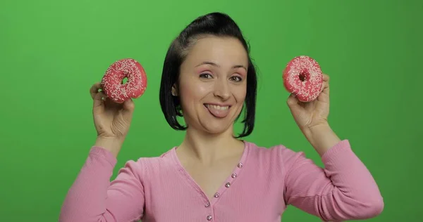 Feliz joven hermosa posando y divirtiéndose con donuts. Clave de croma —  Fotos de Stock