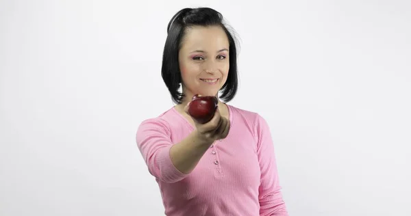 Fiatal gyönyörű vörös almával kínál harapást a nézőnek. Egészséges táplálkozás — Stock Fotó