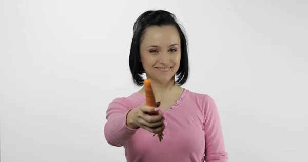 Young beautiful woman with big carrot. Offer bite to viewer. — 스톡 사진