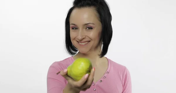 大きくて、新鮮で、ジューシーで、緑の梨を持つ若い美しい女性。観覧者に一口提供 — ストック写真