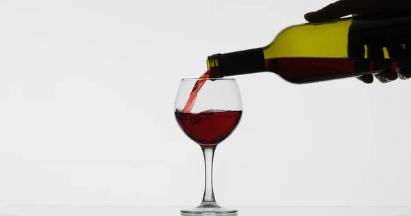 Rosenwein. Rotwein in Weinglas über weißem Hintergrund gießen — Stockfoto