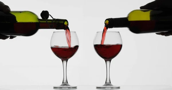 Rose bort. Vörösbor pour két borospohár felett fehér háttér — Stock Fotó