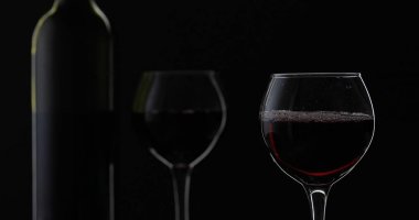 Gül şarabı. Siyah arka plan üzerinde şarap kadehinde kırmızı şarap. Siluet