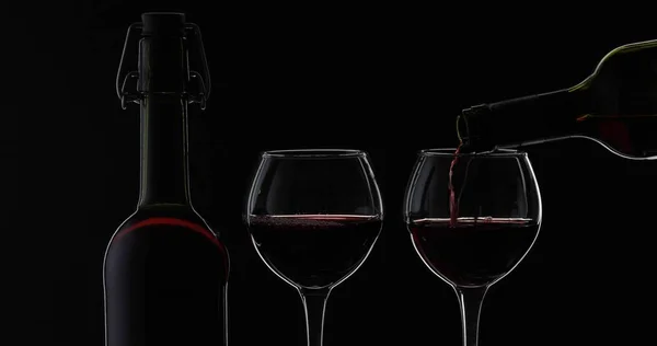 로즈 와인. 레드 와인 검은 배경 위에 와인 유리에 붓는다. 실루엣 — 스톡 사진