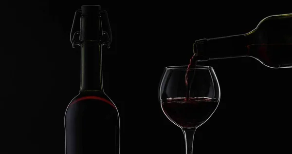 Rosenwein. Rotwein in Weinglas über schwarzem Hintergrund gießen. Silhouette — Stockfoto