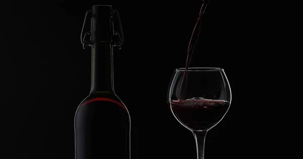 Vino rosato. Vino rosso versare in bicchiere di vino su sfondo nero. Silhouette — Foto Stock