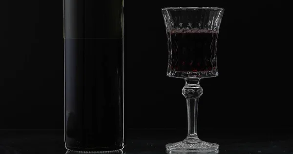 Розовое вино. Красное вино в бокале вина с бутылкой на черном фоне. Силуэт — стоковое фото