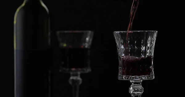 Rosenwein. Rotwein in Weinglas über schwarzem Hintergrund gießen. Silhouette — Stockfoto