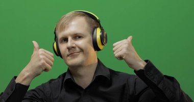 Adam kablosuz sarı kulaklıkla müzik dinliyor ve dans ediyor. Yeşil Ekran