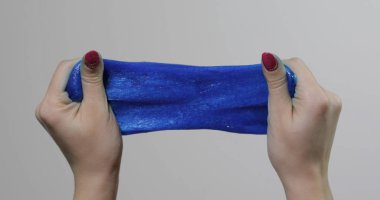 Kadın elleri garip bir şekilde tatmin edici mavi yapışkan maddeyle oynuyor. Stres önleyici