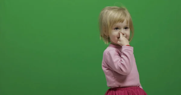 Uma miúda de três anos apanha o nariz. Bonita criança loira. Chave Chroma — Fotografia de Stock