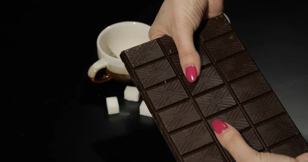 Woman holds black chocolate bar. Close-up shot of woman fingers — 스톡 사진