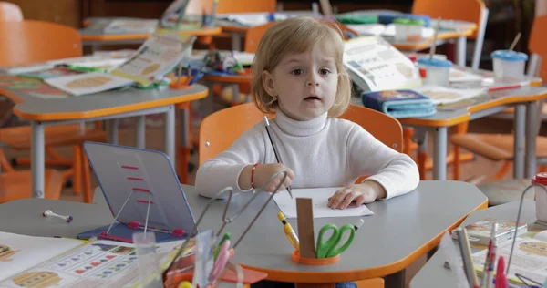 Menina desenho na mesa em sala de aula. Educação. Criança sentada em uma mesa — Fotografia de Stock