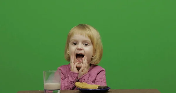 Chica sentada a la mesa con cacao, chocolate y galletas. Clave de croma — Foto de Stock