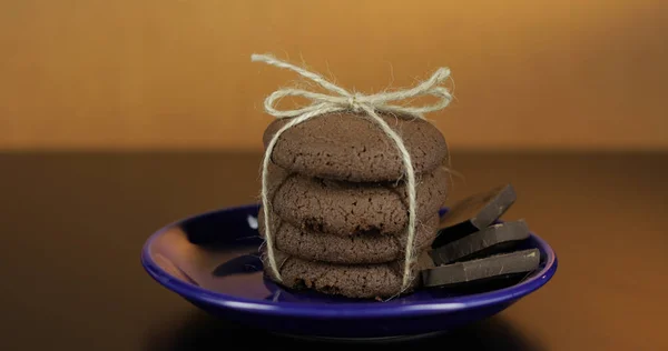 Koyu yüzeyde mavi bir tabak üzerinde lezzetli görünümlü çikolatalı kurabiye. Sıcak arka plan