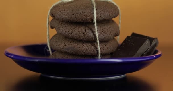 Galleta de chocolate de aspecto sabroso en un plato azul en la superficie oscura. Fondo cálido — Vídeo de stock