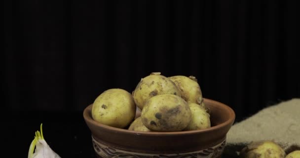 Vrouw hand neemt aardappelen in stapel een voor een. Vuile rauwe aardappelen op een bord — Stockvideo