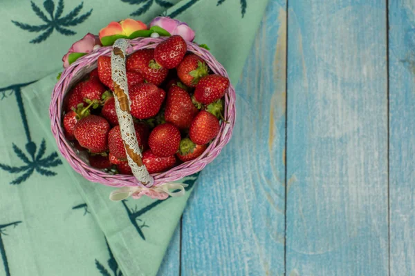 Strawberries in a small basket on the blue wooden background. Place for text