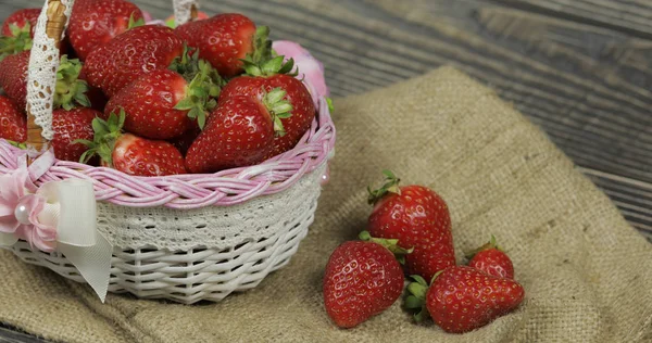 Fresas en una pequeña canasta sobre la mesa de madera. Lugar para su logotipo o texto — Foto de Stock