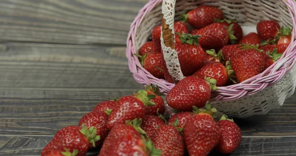 Strawberries in a small basket on the wooden table. Place for your logo or text