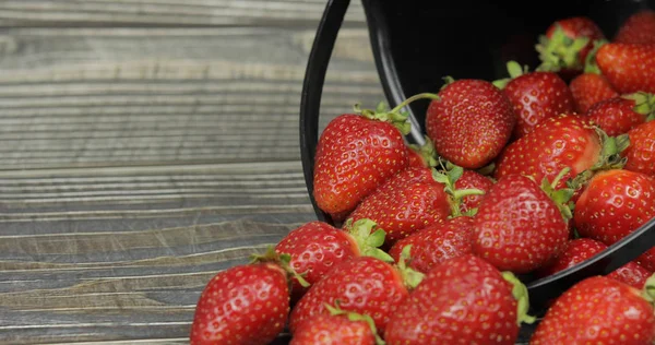 Fresas en pequeño cubo negro sobre mesa de madera. Lugar para su logotipo o texto — Foto de Stock